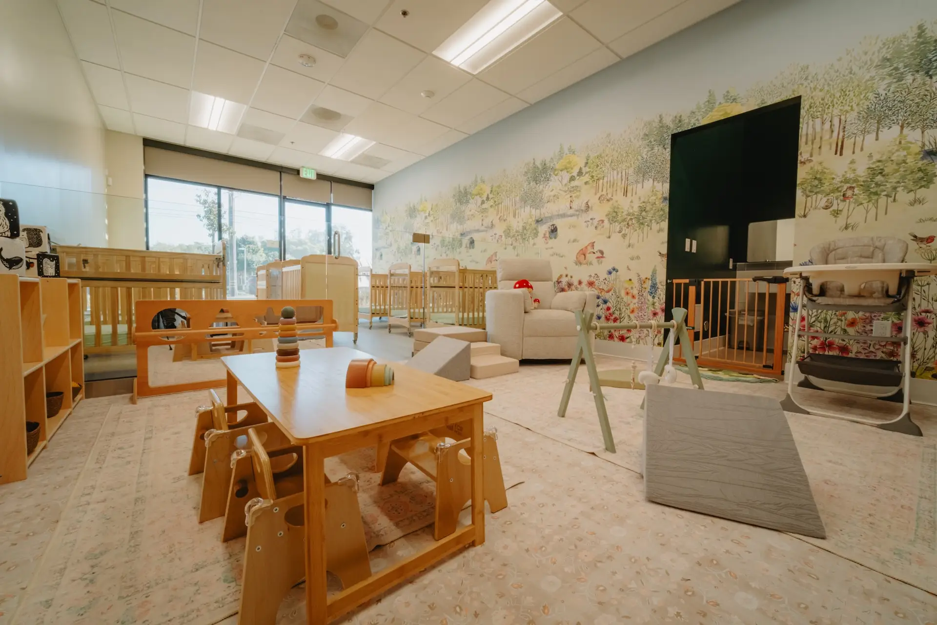 Infant classroom with woodland mural and play area at Ohana Montessori